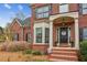 Welcoming brick home entrance featuring a covered porch, flowerpots and manicured bushes at 4155 Summit Gate Dr, Suwanee, GA 30024