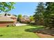 Wide view of the backyard showcasing green grass, trees, and a brick home with a garage at 2849 Livsey Woods Dr, Tucker, GA 30084