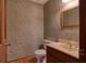 Powder room with decorative wallpaper, hardwood floors, and a vanity with a marble countertop at 1510 Wood Thrush Way, Marietta, GA 30062