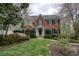 Charming red brick two-story home featuring a beautifully landscaped front yard with mature trees and flowering shrubs at 1510 Wood Thrush Way, Marietta, GA 30062