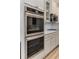 Close-up of double ovens and gas cooktop, complemented by white cabinets and sleek hardware, in a modern kitchen at 4560 Evandale Way, Cumming, GA 30040