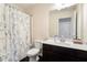 Cozy bathroom with a shower and tub, dark wood vanity, white countertop, and decorative floral shower curtain at 7701 Haynes Park Pl, Lithonia, GA 30038
