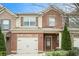 Brick townhome with a one-car garage, covered entry, and manicured landscaping at 7701 Haynes Park Pl, Lithonia, GA 30038