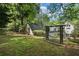 View of backyard and rear elevation with mature trees, grass and white brick home with detached shed at 1503 Emory Ne Rd, Atlanta, GA 30306