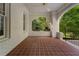 Covered front porch with red tiled floor, brick columns, and garden view at 1503 Emory Ne Rd, Atlanta, GA 30306