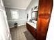 Bright bathroom showcasing tiled floors, wood vanity and storage cabinet at 1718 Pucketts Sw Dr, Lilburn, GA 30047