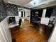 Cozy living room with beautiful wood floors, wainscoting, and black and white patterned wallpaper at 1718 Pucketts Sw Dr, Lilburn, GA 30047