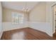 Dining room featuring hardwood floors, neutral walls, a chandelier, wainscoting, and a window at 5882 Riverside Walk Dr, Sugar Hill, GA 30518