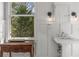 Charming all-white bathroom with wood-paneled walls, pedestal sink, and window views at 1311 Berwick Ne Ave, Atlanta, GA 30306