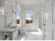 Bright, all-white bathroom with marble floors, pedestal sink, and a tub with shower at 1311 Berwick Ne Ave, Atlanta, GA 30306