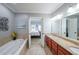Bright primary bathroom with double vanity, granite countertops, soaking tub, and doorway to the main bedroom at 402 River Vista Dr, Atlanta, GA 30339