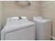 Clean laundry room with washer, dryer and storage shelving at 1170 Livery Cir, Lawrenceville, GA 30046