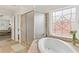 Bright bathroom with a shower, tub, decorative window and neutral tile at 426 Vera Park Pl, Alpharetta, GA 30022