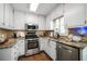Well-lit kitchen boasts stainless steel appliances, white cabinets, granite countertops, and tile backsplash at 4783 Deer Chase, Powder Springs, GA 30127