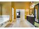 A view of a bathroom with a soaking tub, tile flooring, double sinks with cabinets and multiple doorways at 415 Damascus Ct, Fairburn, GA 30213