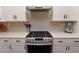 Close up of gas stove and vent hood with white shaker cabinets and subway tile backsplash at 1494 Addison Pl, Decatur, GA 30033