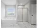 Bright bathroom featuring a soaking tub, glass-enclosed shower, and white marble tile flooring at 210 Millpond Pkwy, Villa Rica, GA 30180