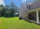 A spacious backyard with lush lawn, mature trees, brick exterior, and a covered patio at 828 Cooper Lakes Ct, Grayson, GA 30017