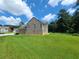 Backyard with spacious lawn and landscaped area, brick and vinyl siding, and mature trees at 828 Cooper Lakes Ct, Grayson, GA 30017