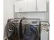 Modern laundry room featuring a front load washer and dryer with upper storage cabinets at 139 Rushing View Gln, Dallas, GA 30157