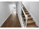 Hallway features hardwood floors, white trim, and carpeted stairs with black metal railings at 280 Mcgiboney Ln, Covington, GA 30016