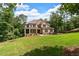 Picturesque two-story brick home with a covered porch and a well-maintained lawn, surrounded by a forest backdrop at 7580 Sunridge Ln, Douglasville, GA 30135