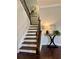 Elegant staircase with wood steps, a black railing, and a decorative table with a lamp at 7580 Sunridge Ln, Douglasville, GA 30135