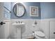 Powder bathroom featuring elegant pedestal sink, round mirror and wainscoting at 5950 Thoroughbred Way, Suwanee, GA 30024