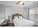 Bedroom with a ceiling fan, neutral walls, plush headboard, and a large window for natural light at 5950 Thoroughbred Way, Suwanee, GA 30024