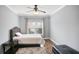 Neutral bedroom with hardwood floors, a tufted headboard, a soft rug, and a window at 5950 Thoroughbred Way, Suwanee, GA 30024