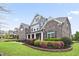 Beautiful landscaped front yard leading up to a grand two-story brick home with a covered porch at 5950 Thoroughbred Way, Suwanee, GA 30024
