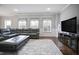 Spacious living room features a leather sectional, plush rug, hardwood floors and large-screen TV at 5950 Thoroughbred Way, Suwanee, GA 30024