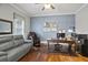 Cozy home office with hardwood floors, wainscoting, a large desk, and a comfortable leather sofa at 5950 Thoroughbred Way, Suwanee, GA 30024