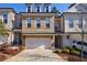 Attractive brick townhome featuring a two-car garage, dormer windows, and professionally landscaped front yard at 5010 Towneship Creek Rd, Roswell, GA 30075