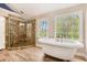 Bright bathroom with a soaking tub and a glass enclosed tile shower with wood look floors at 5145 Southlake Dr, Alpharetta, GA 30005
