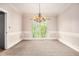 Empty dining room with chandelier, wainscotting, neutral carpet and big window at 5145 Southlake Dr, Alpharetta, GA 30005