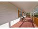 Covered front porch with white columns, stained wood flooring and railings, and wood-stained window shutters at 6690 Pine Ridge Cir, Cumming, GA 30041