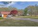 Ranch-style house with a red roof, attached garage, covered porch, and a spacious front yard with mature tree at 6690 Pine Ridge Cir, Cumming, GA 30041