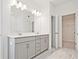 Bright bathroom featuring a double vanity with gray cabinetry, a large mirror, and modern lighting fixtures at 4212 Adler Cir, Buford, GA 30519
