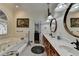 Bright bathroom featuring double sinks, elegant mirrors, and a soaking tub with decorative art at 2962 Norman Cir, Duluth, GA 30096