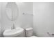 Modern powder room with pedestal sink, round mirror, and fixtures, offering a clean and elegant space at 4457 Watson Ridge Dr, Stone Mountain, GA 30083