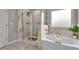 Bathroom featuring a glass-enclosed shower, soaking tub and stylish neutral tile at 1105 Alaska St, Hampton, GA 30228