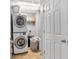 This laundry room features a stacked washer and dryer maximizing space, next to a door and shelves at 2155 Westwind Dr, Roswell, GA 30075