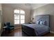 Bright bedroom featuring a large arched window, hardwood floors, and a calming gray color scheme at 3053 Cambridge Hill Dr, Dacula, GA 30019