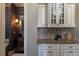 Butler pantry with custom cabinets, granite countertops, decorative backsplash, and adjoining powder room at 3053 Cambridge Hill Dr, Dacula, GA 30019