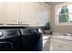 Well-organized laundry room with modern appliances, white cabinets, sleek countertop, and a bright window at 3053 Cambridge Hill Dr, Dacula, GA 30019