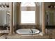 Beautiful primary bathroom featuring a large soaking tub, dual vanities, and decorative columns at 3053 Cambridge Hill Dr, Dacula, GA 30019