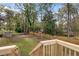 Backyard featuring a large grassy area, a wooded perimeter, and a well-maintained wooden deck at 1185 Winterberry Ct, Lawrenceville, GA 30043