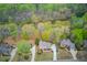 Stunning aerial view of a brick home nestled amongst lush trees with a long driveway and well manicured lawn at 1343 Riverview Run Ln, Suwanee, GA 30024