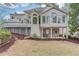Rear exterior showcasing a spacious deck, manicured landscaping and covered patio at 1343 Riverview Run Ln, Suwanee, GA 30024